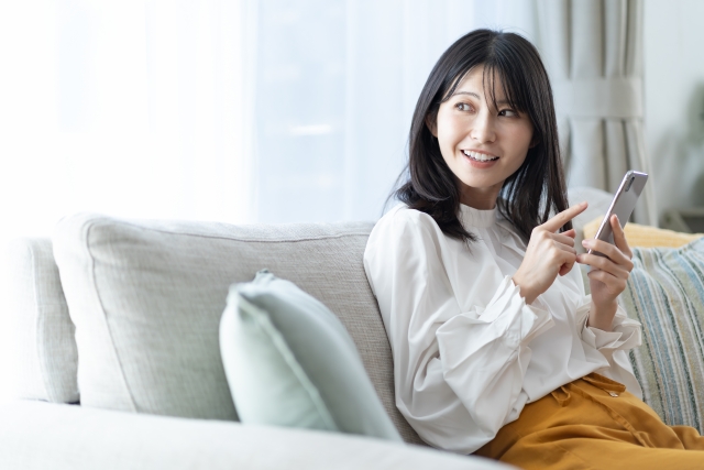 ソファで携帯を持つ日本人女性
